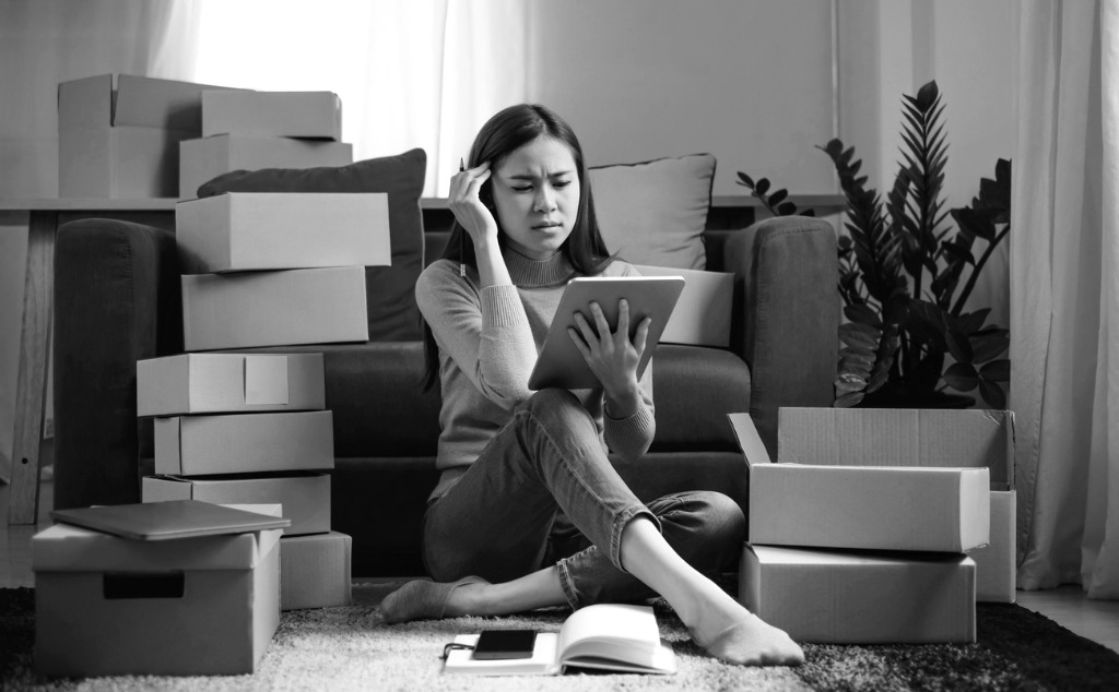 Woman sitting next to boxes in her house frustrated