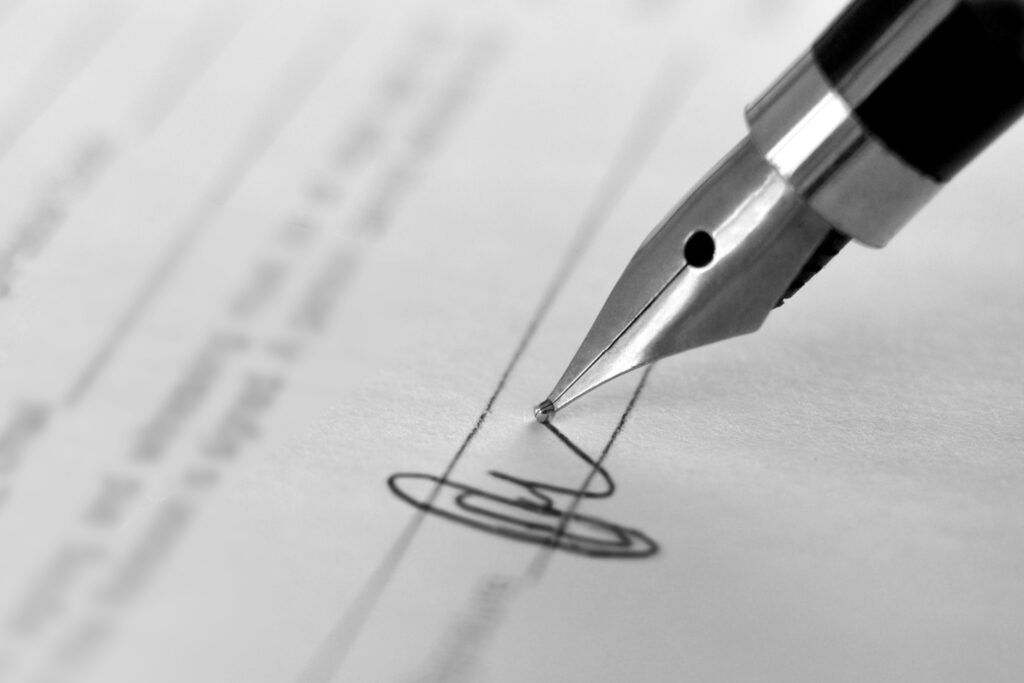 Pen writing a signature on a document