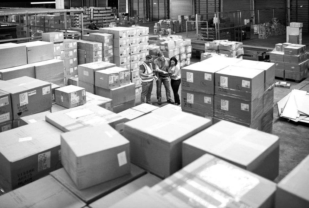 Three people working together in a warehouse full of boxes